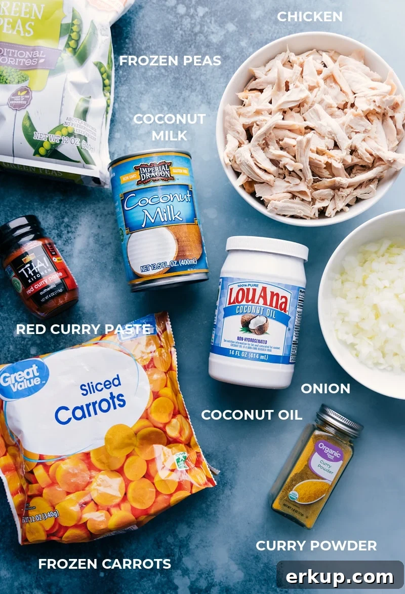 All the ingredients for this recipe prepped and laid out for easy assembly, including peas, coconut milk, shredded chicken, red curry paste, coconut oil, diced onions, sliced carrots, and seasonings.