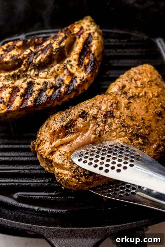 Juicy Oven-Roasted Turkey Tenderloin Recipe 10 Someone is using tongs to flip a tenderloin of turkey over on a cast iron skillet grill.