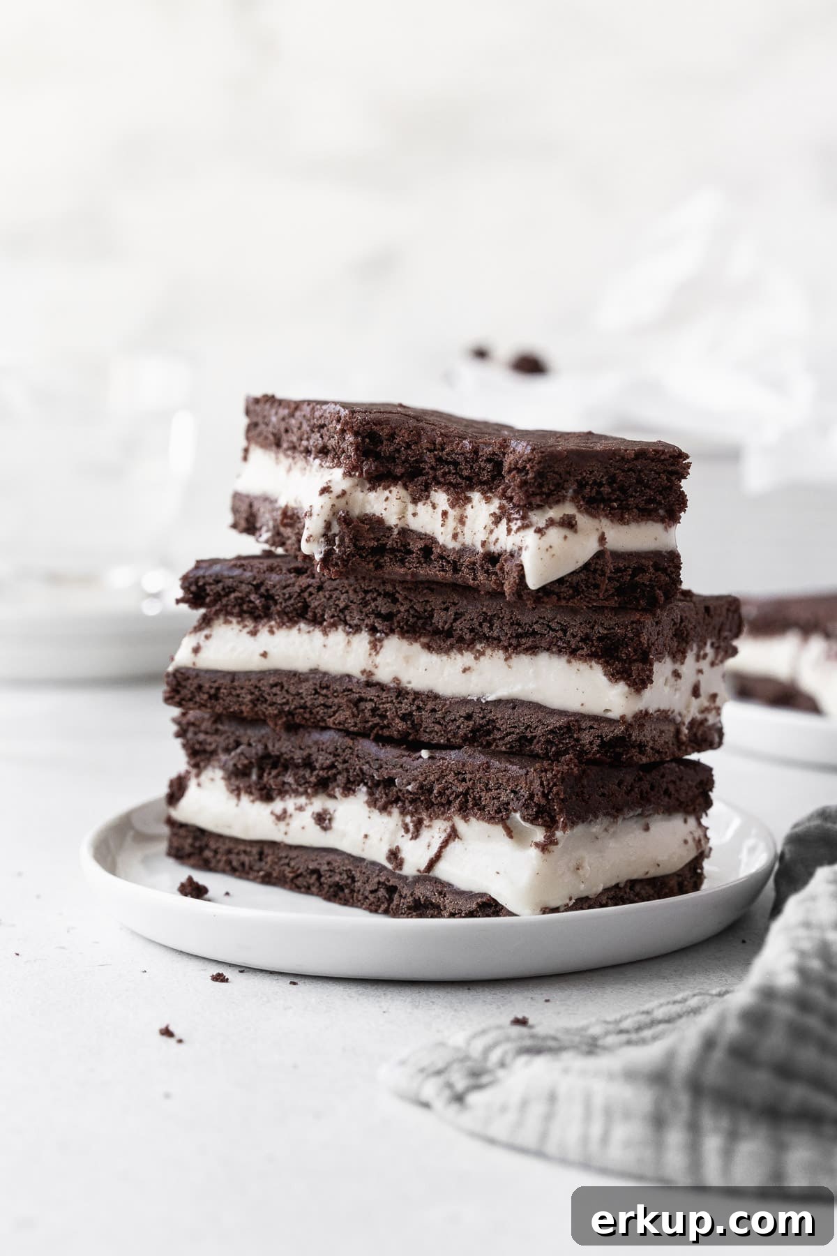 A stack of ice cream sandwich cookies on a small white dish with a large bite taken out of one of the cookies.