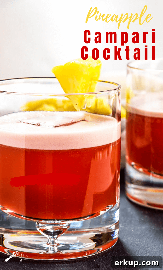 Sideview of two rocks glasses filled with a Campari Drink and garnished with pineapple.