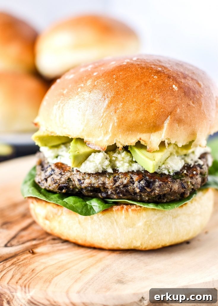 spicy black bean burgers with avocado and pesto goat cheese on a bun.