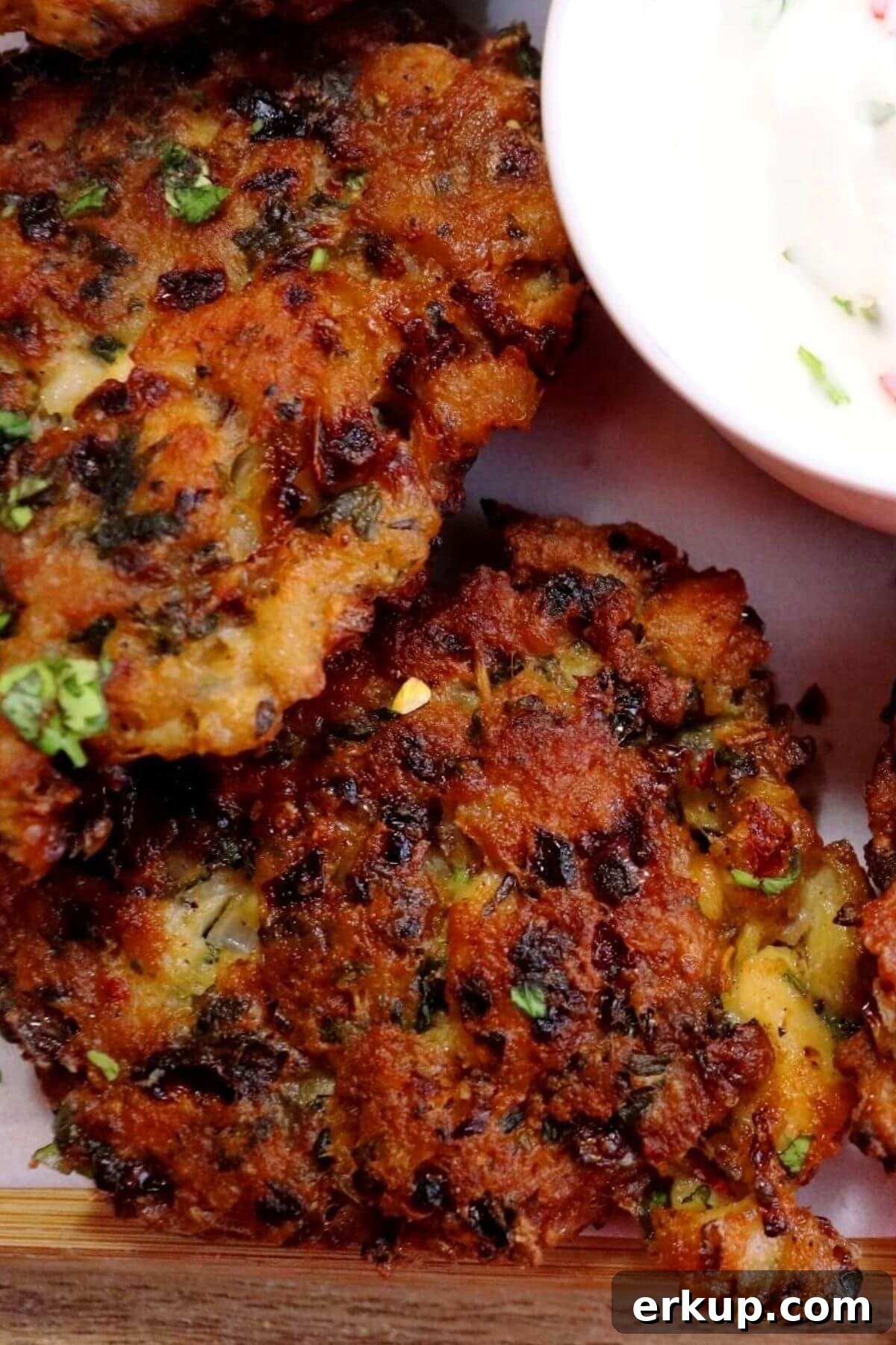 close-up of chicken fritters placed on a white colored plate with a dip.
