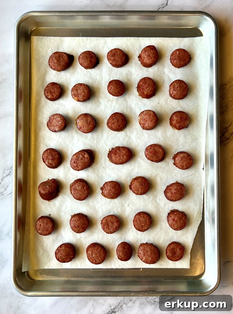 Cooked smoked sausage on sheet pan lined with parchment paper.