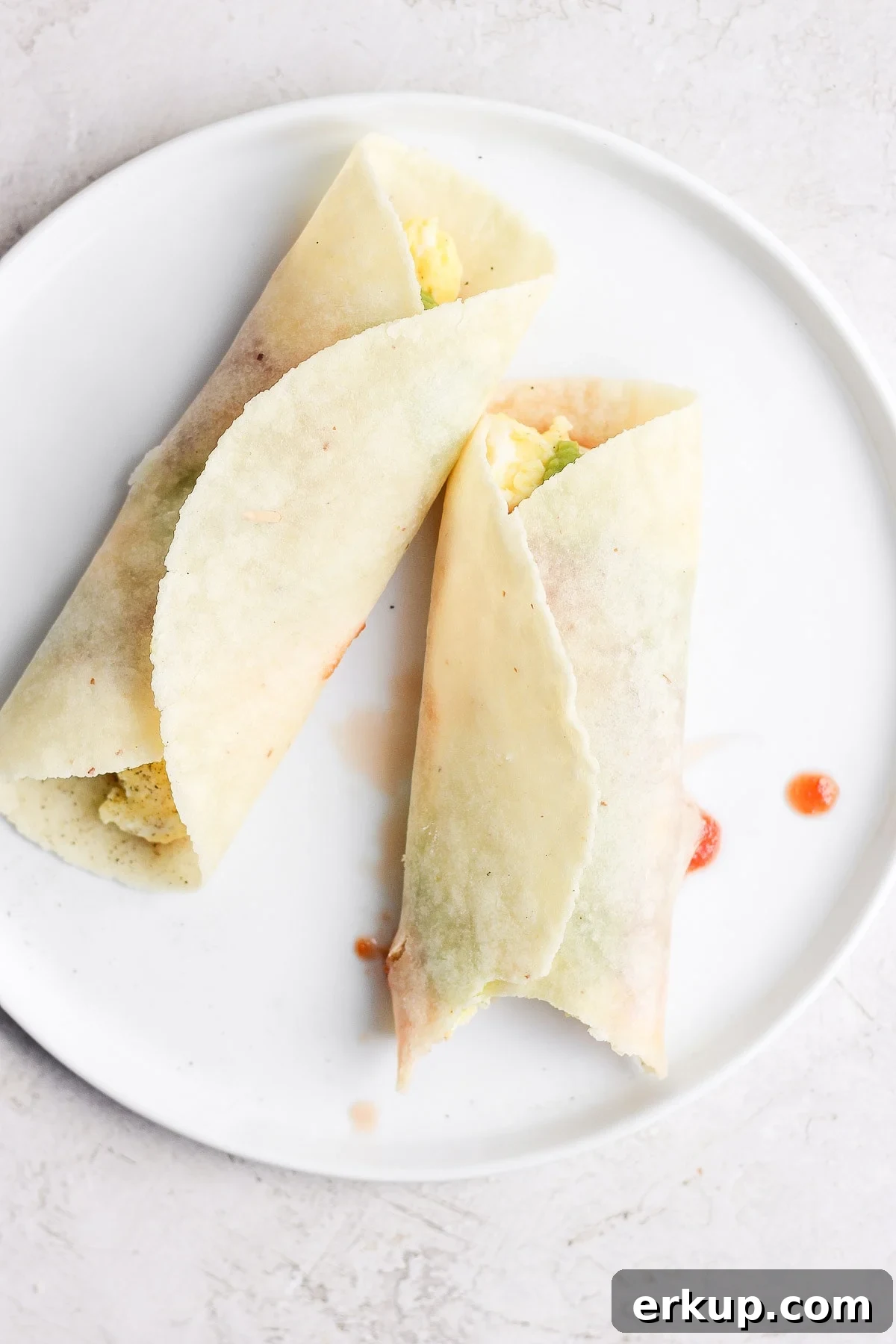 High-Protein Breakfast Tacos with Eggs and Avocado 6 Two breakfast tacos on a white plate.