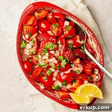Strawberry and tomato salad in a red bowl.