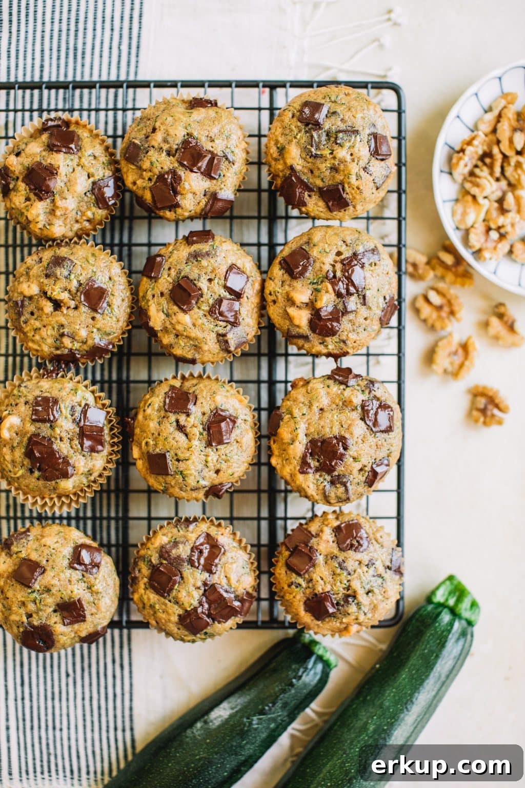 zucchini muffins with chocolate chips in wire rack with fresh zucchini and walnuts