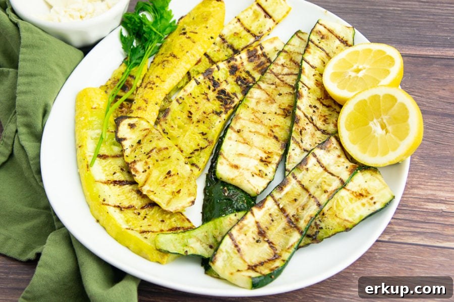 a white platter of grilled summer squash with a sliced lemon