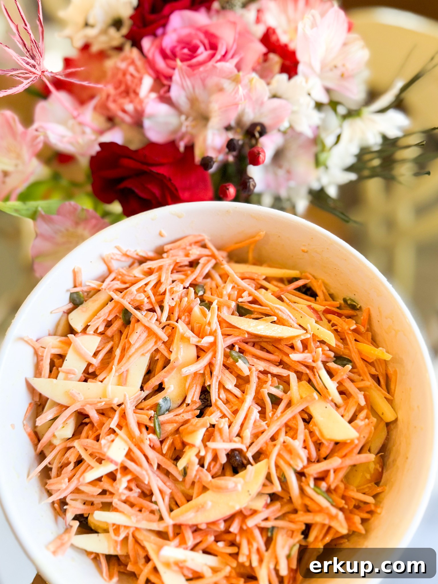 Carrot slaw served in a bowl with pumpkin seeds on top