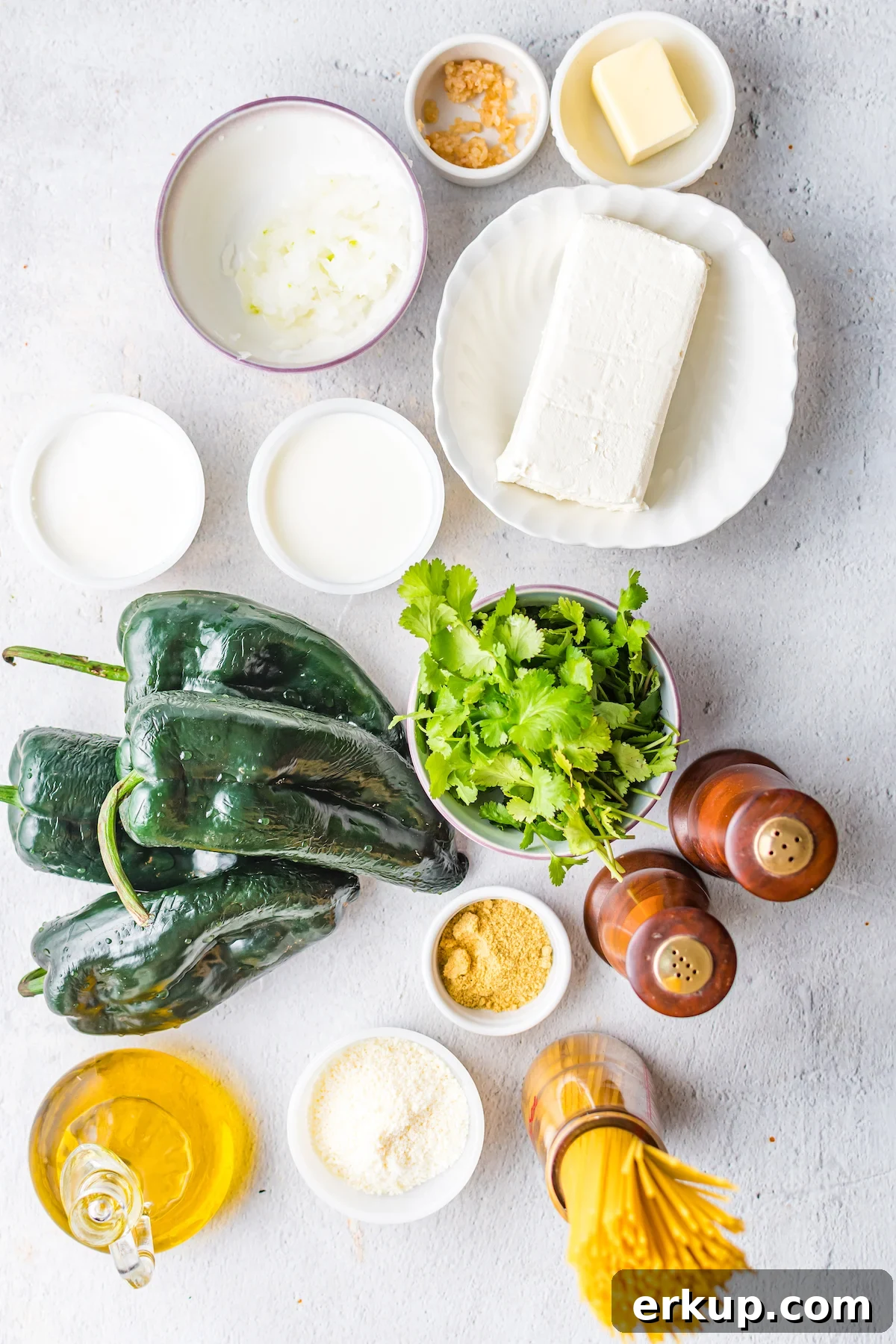 Overhead shot of the ingredients you need to make green Mexican spaghetti. Fresh poblanos, cream cheese, cilantro, noodles, salt, pepper, and oil.