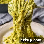 A close-up of creamy green poblano sauce coating spaghetti.