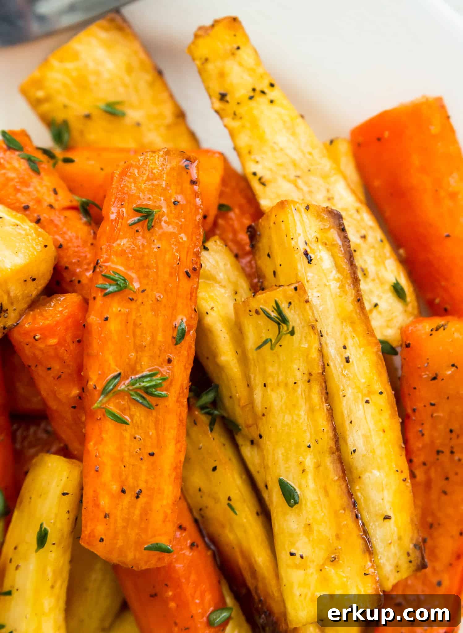 A bowl of honey glazed carrots and parsnips topped with fresh thyme.