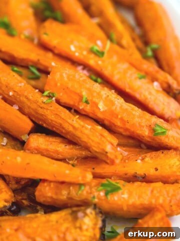 A plate of roasted, sliced carrots with parsley on top for garnish.