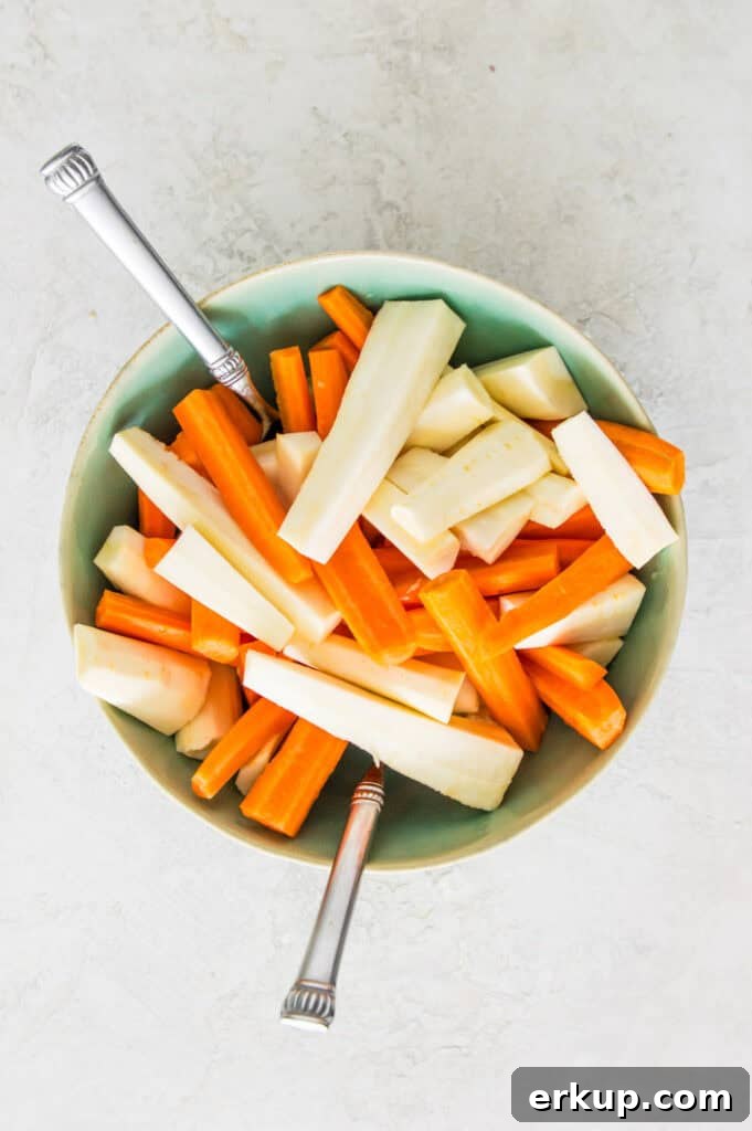 A bowl filled with chopped and peeled carrots and parsnips.