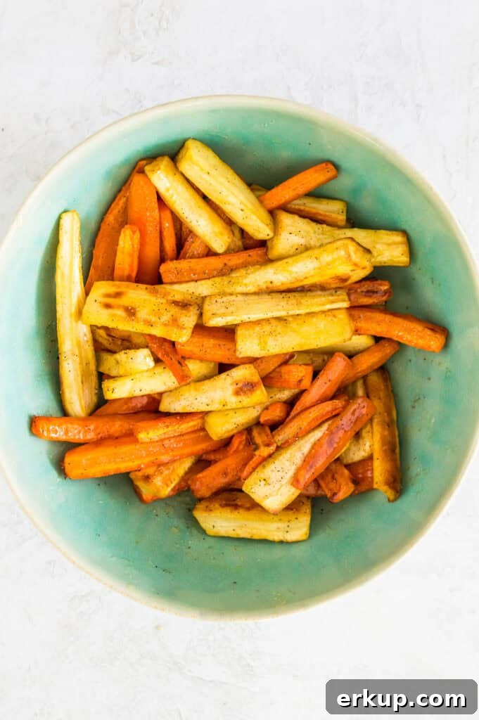 A bowl filled wth roasted carrots and parsnips.