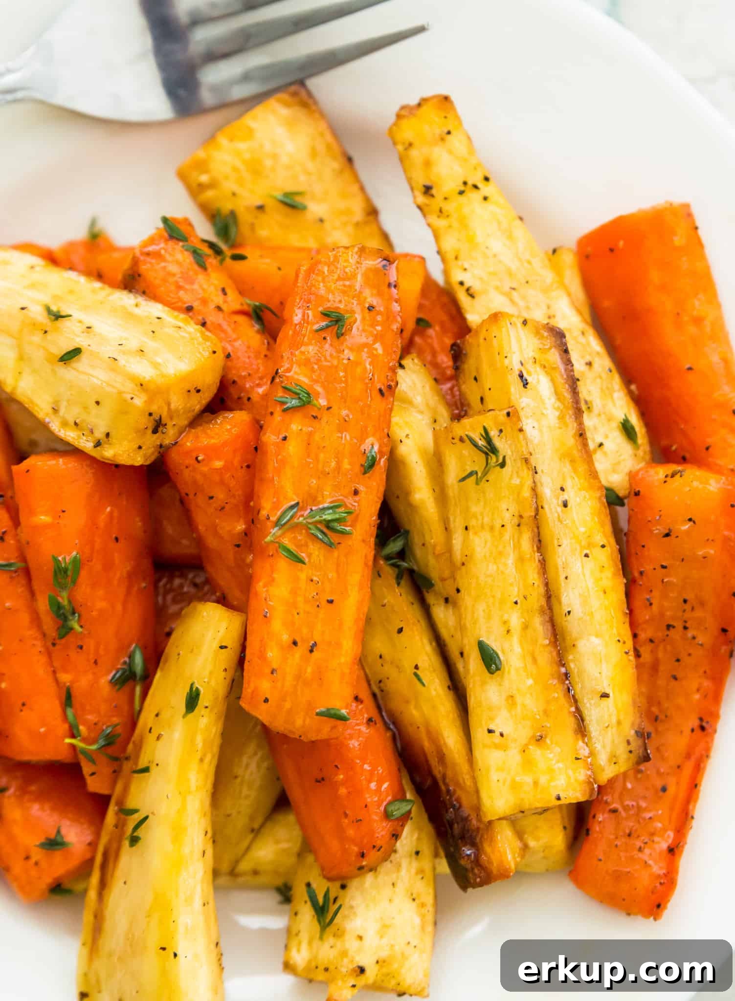 A plate full of honey glazed carrots and parsnips topped with fresh thyme.