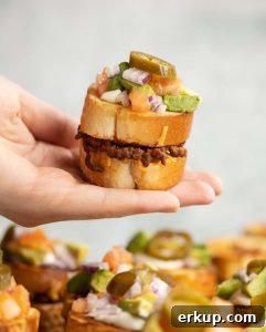 hand holding mini sandwich above board of sandwiches