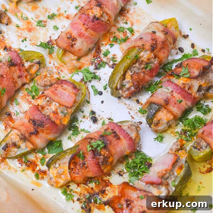 pickles stuffed with cheeseburger wrapped in bacon on pan.