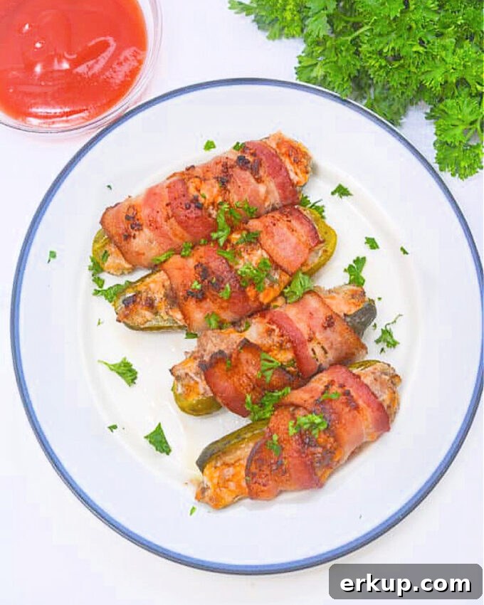Keto Bacon-Wrapped Cheeseburger Pickle Poppers Recipe 3 bacon wrapped pickle poppers on a plate.