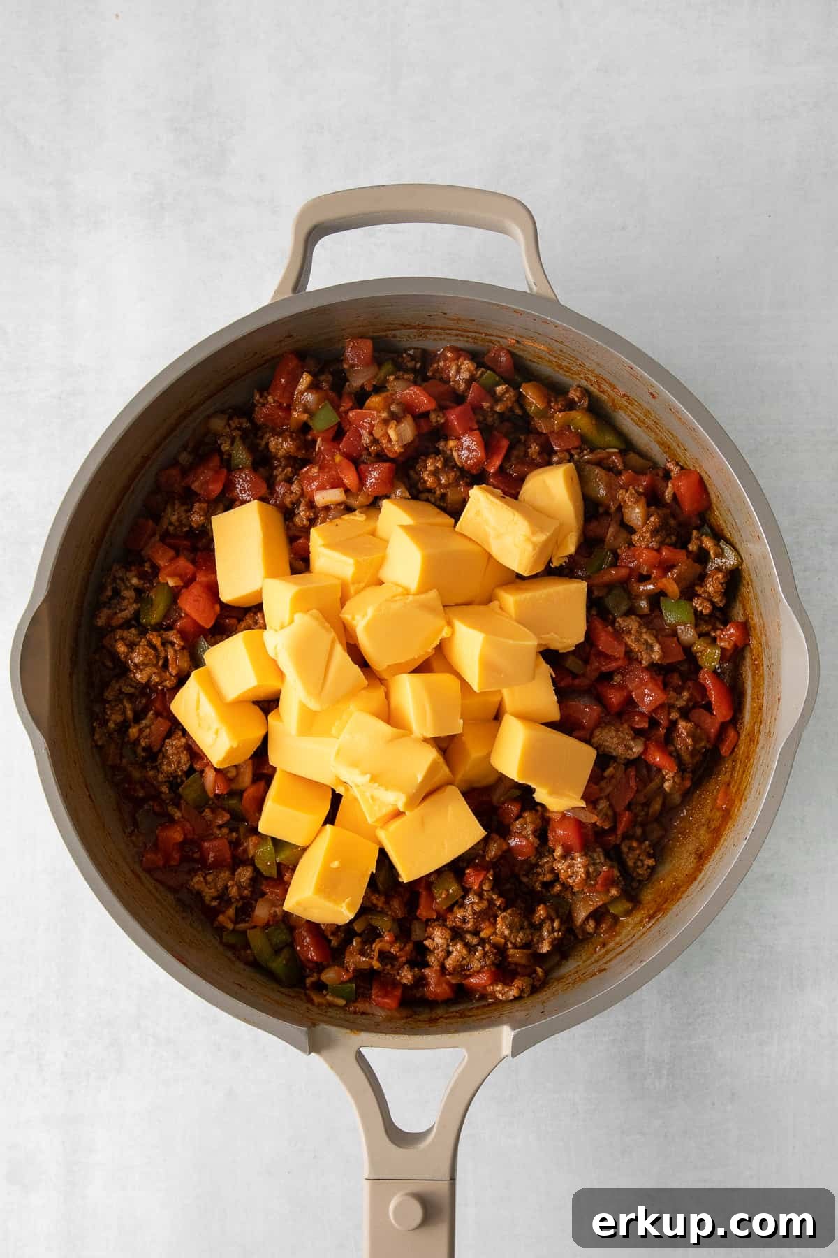Velveeta chili cheese dip in a skillet topped with diced Velveeta cheese.