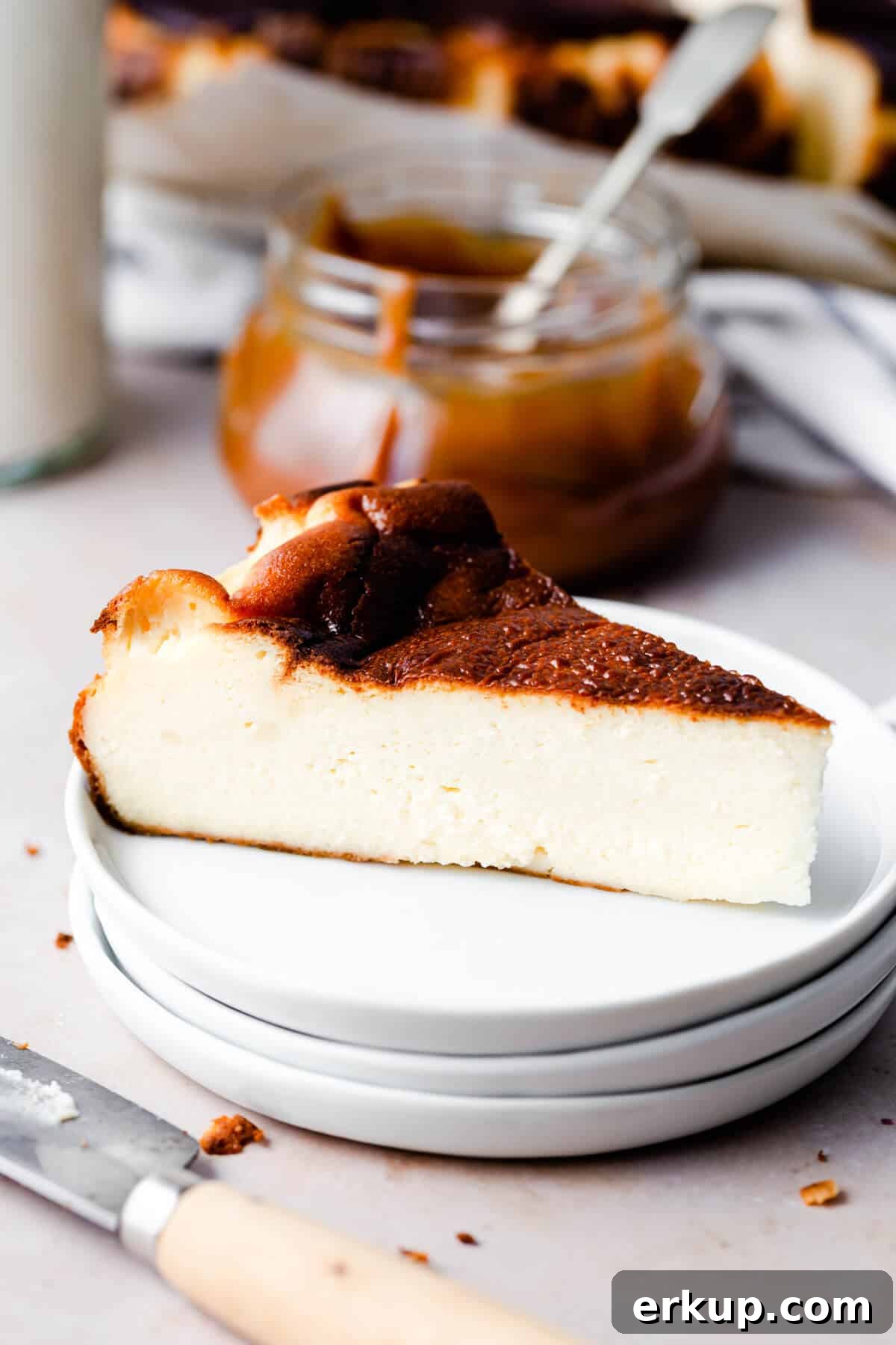 side close up of a slice of cheesecake on a stack of three white plates