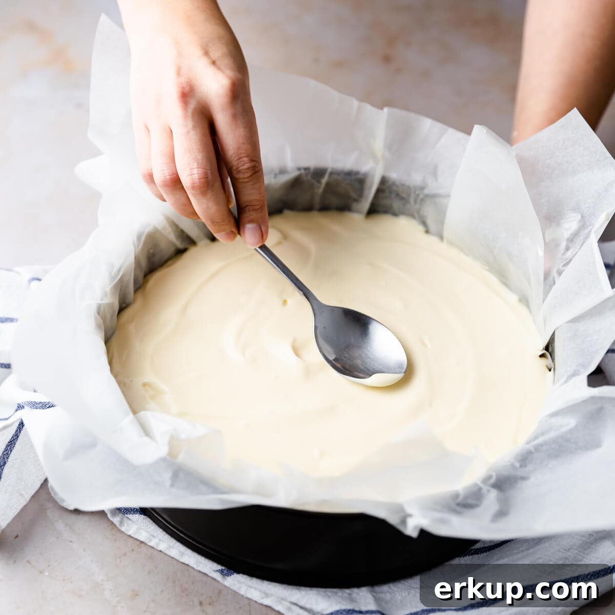 top of the cheesecake being smoothed out with the back of the spoon.