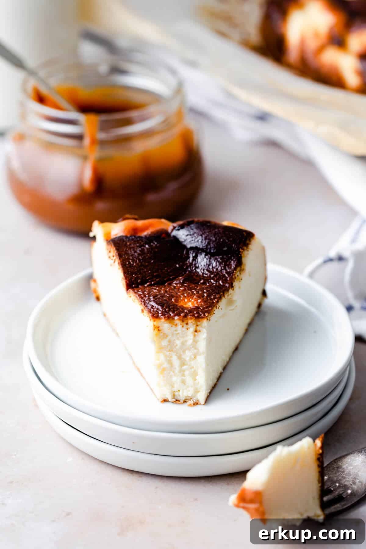straight ahead close up of a slice of cheesecake with bite missing, revealing the creamy texture
