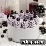 A soft purple grape cake using a cake mix and topped with buttercream swirls and black grapes.