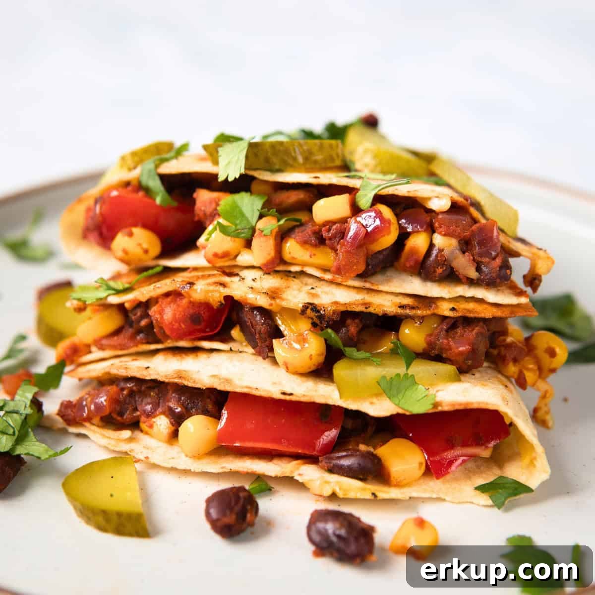 Black Bean Quesadillas Recipe with Creamy Avocado Salsa 2 filled black bean quesadillas on a white plate.