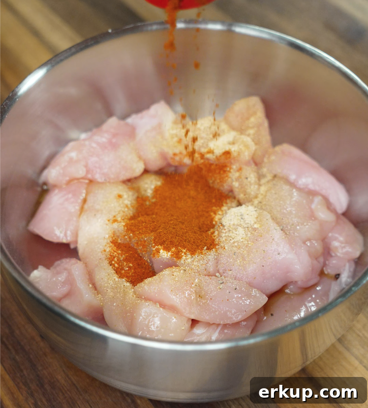 Hot Honey Butter Chicken Recipe 4 Raw chicken in a metal bowl being seasoned with spices for sriracha honey butter fried chicken