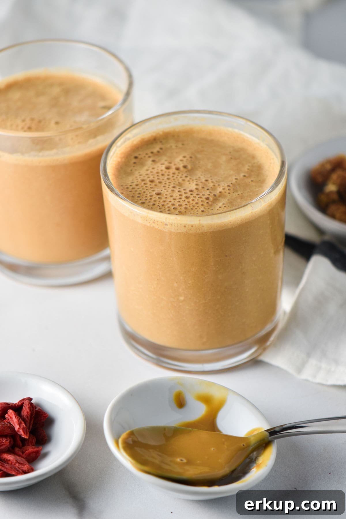 Creamy Sunflower Seed Butter and Maca Smoothie Recipe 2 Two maca smoothies next to a spoon with sunbutter and a white cloth