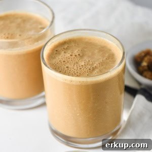 Creamy Sunflower Seed Butter and Maca Smoothie Recipe 11 Two maca smoothies in clear glasses with a small bowl of dried mulberries on the side.