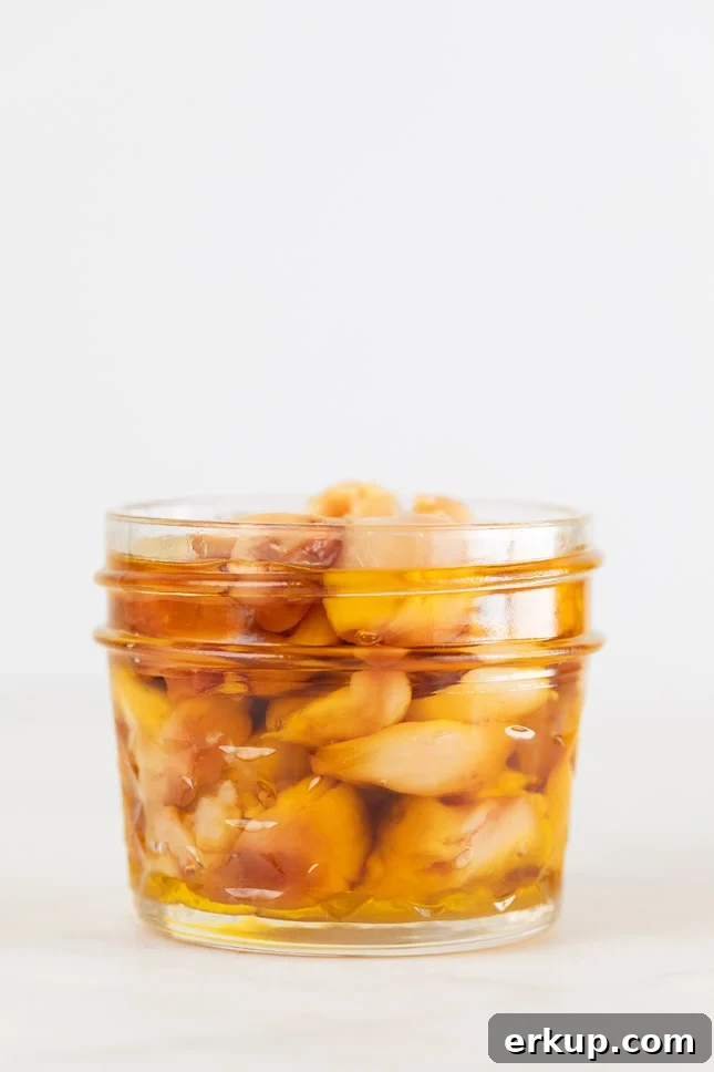 How to Roast Garlic in the Oven for Sweet, Spreadable Cloves 2 A side shot of a glass jar with roasted garlic cloves and covered with oil