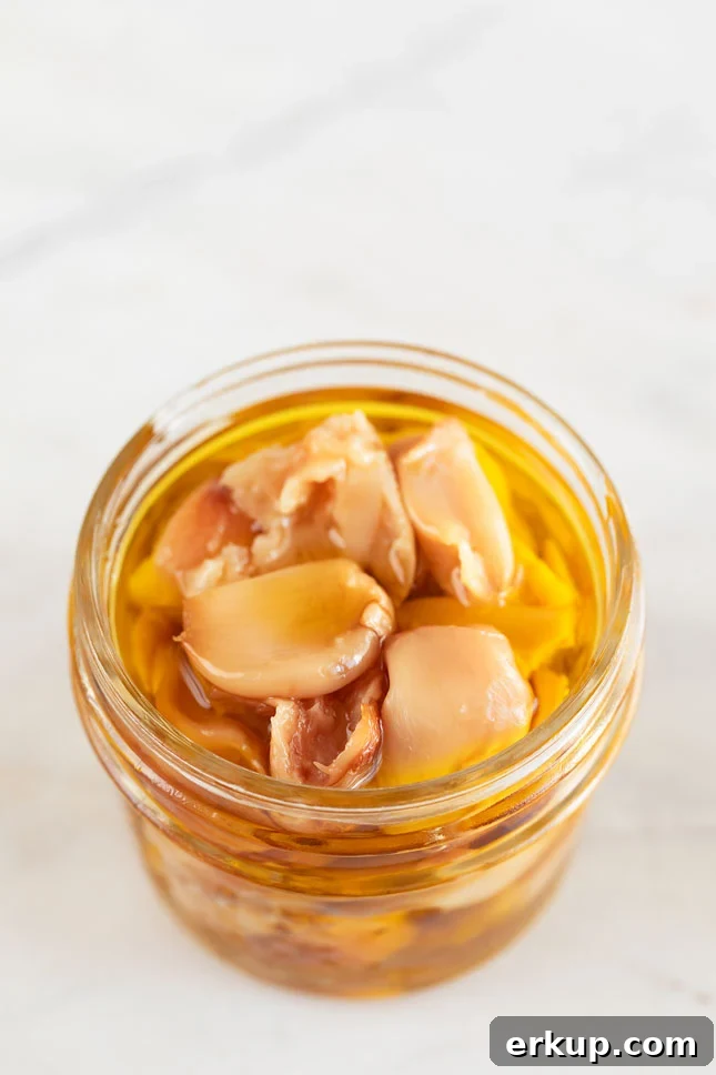 How to Roast Garlic in the Oven for Sweet, Spreadable Cloves 5 A small glass container with roasted garlic cloves and covered with extra virgin olive oil