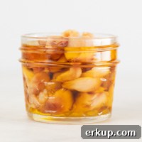 How to Roast Garlic in the Oven for Sweet, Spreadable Cloves 6 A small picture of a glass container with roasted garlic and covered with oil