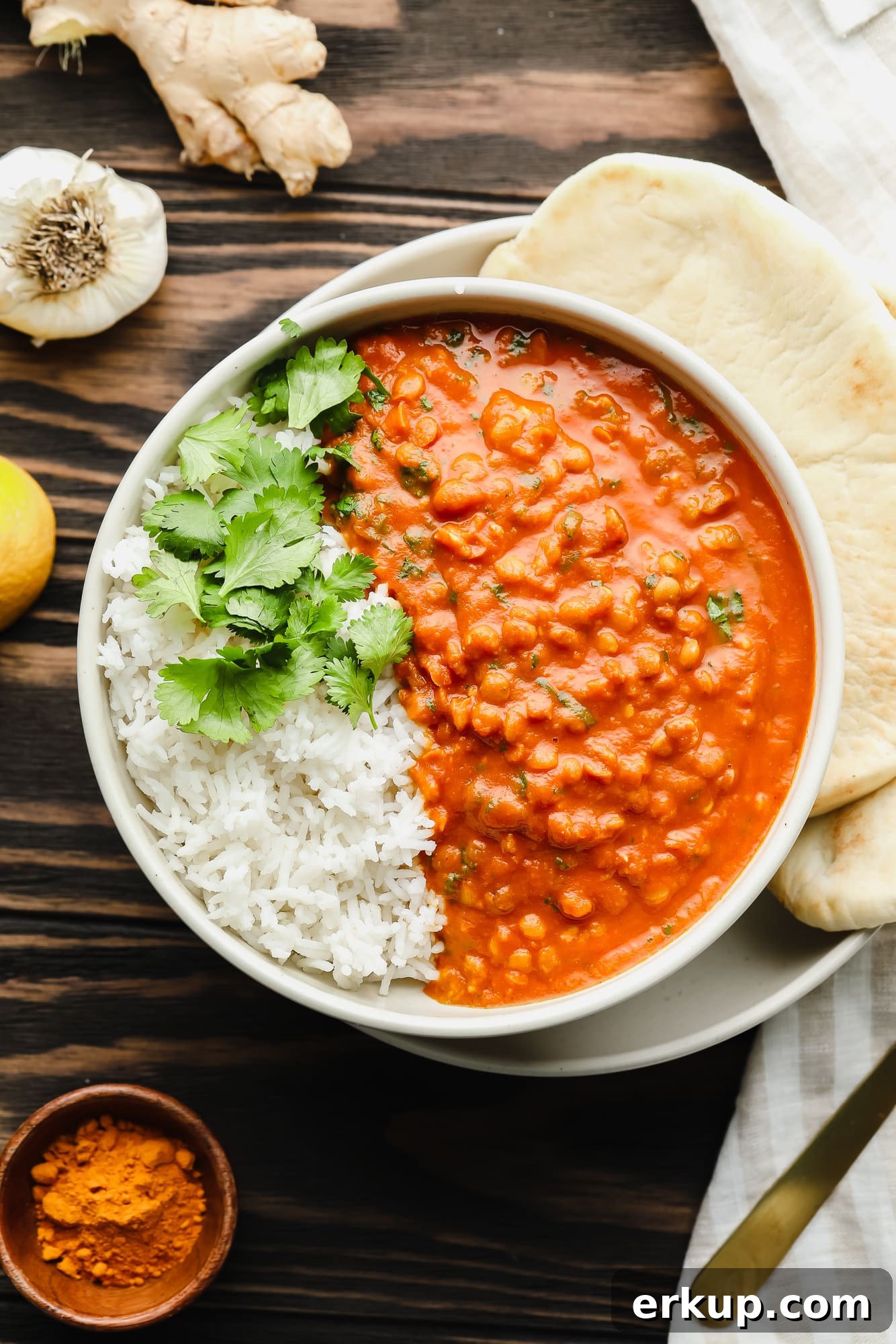 lentil curry with white rice and cilantro in a large bowl with naan on the side.