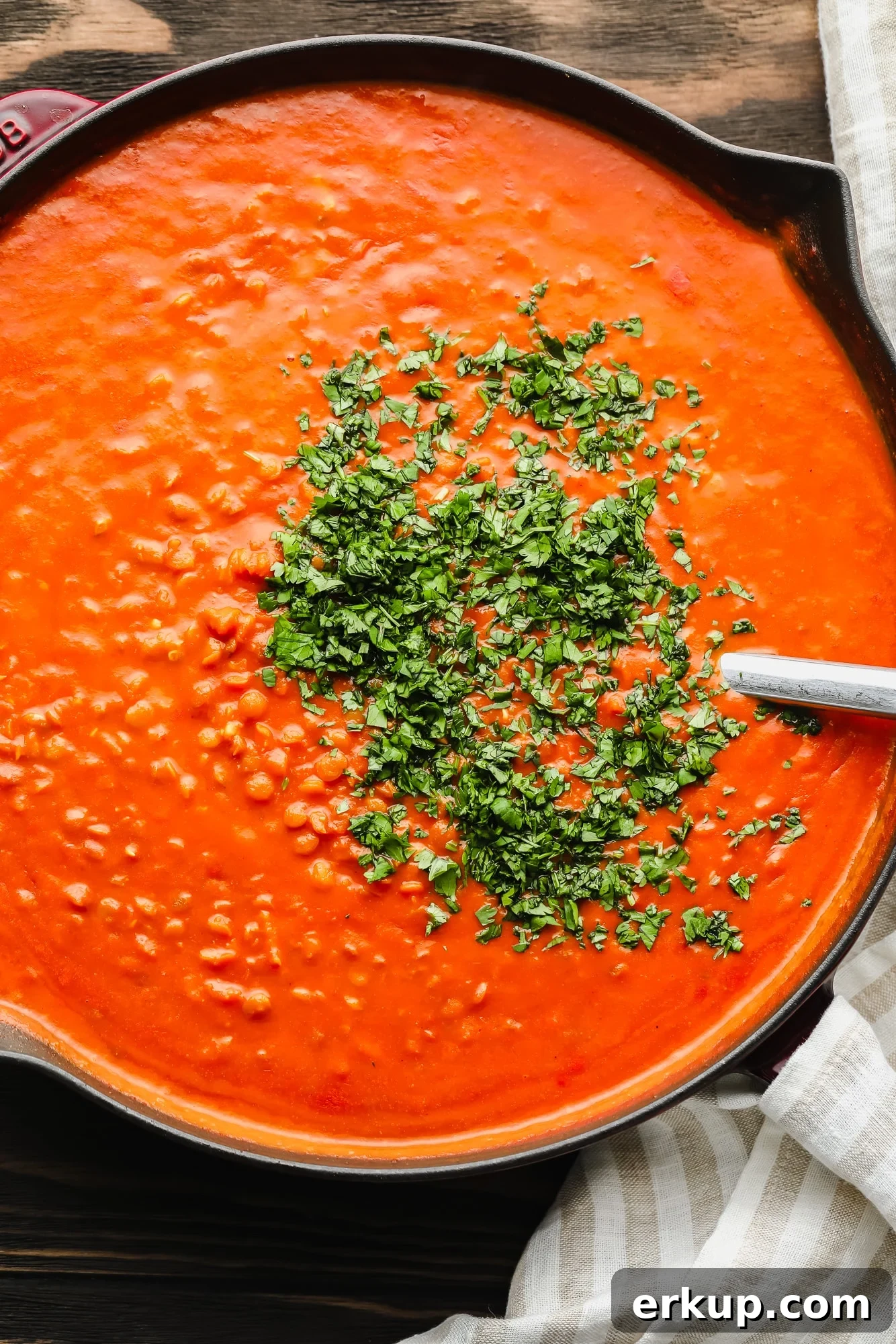 lentil curry topped with chopped cilantro leaves in a large black pot.