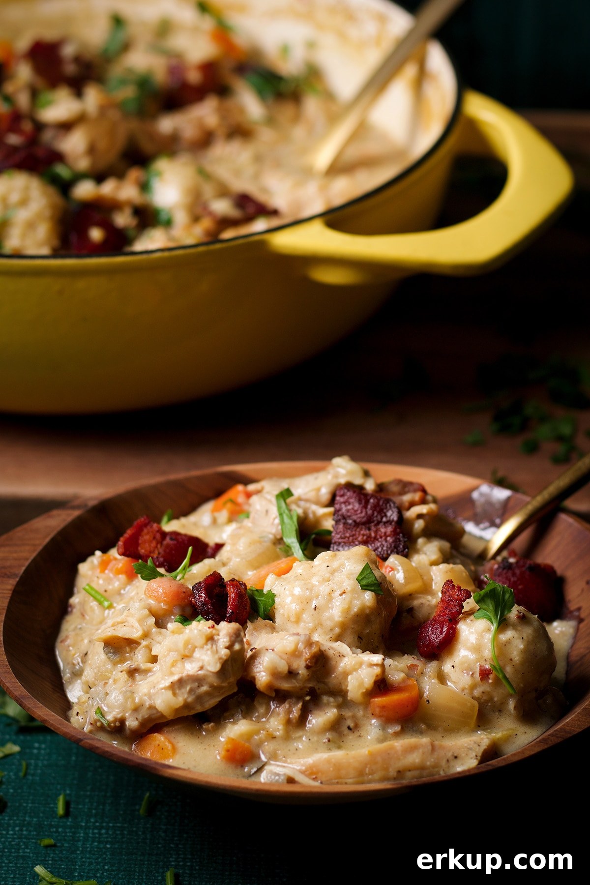 A wooden bowl filled with a serving of chicken and wild rice soup with parmesan dumplings. 