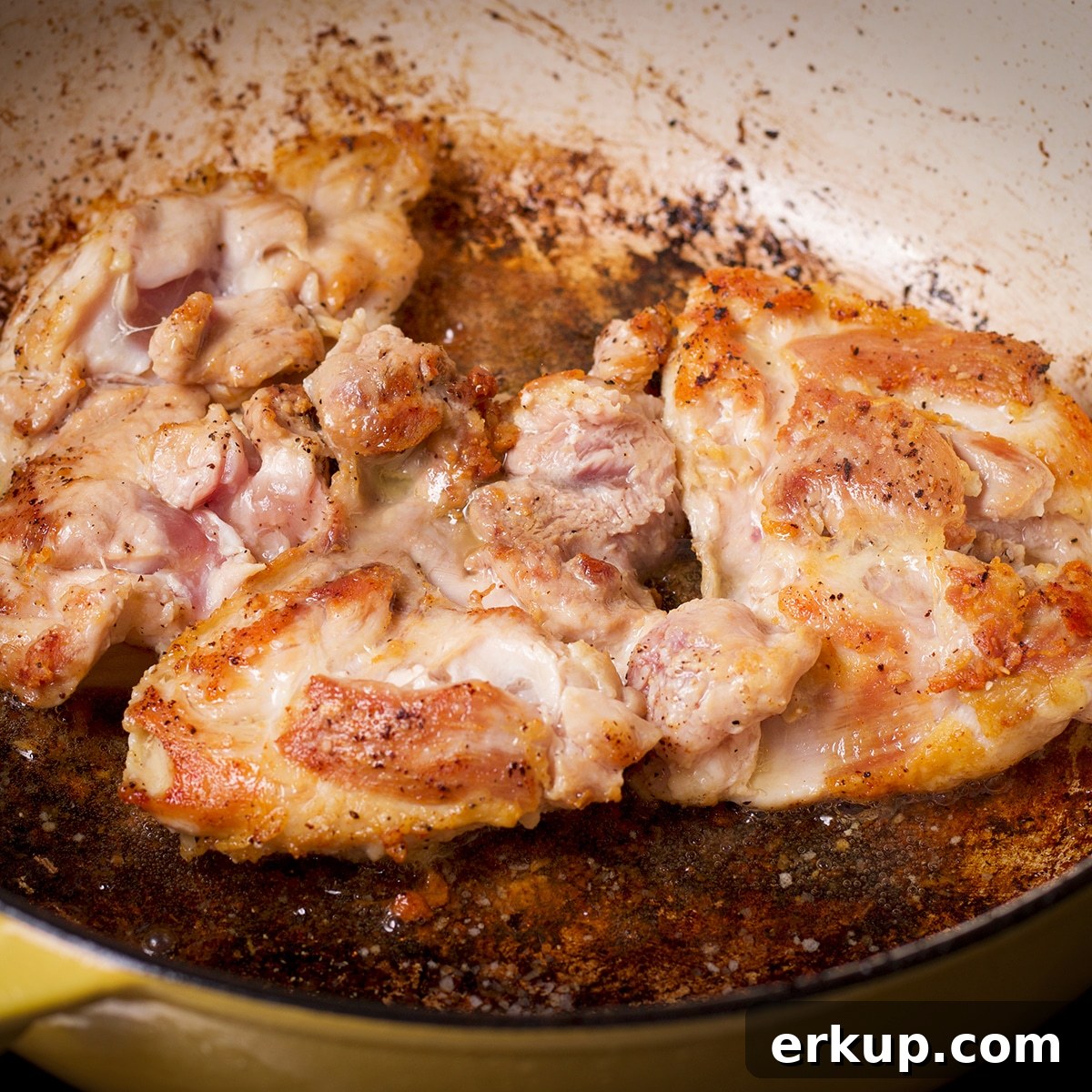 Boneless, skinless chicken thighs browning in a hot pan.