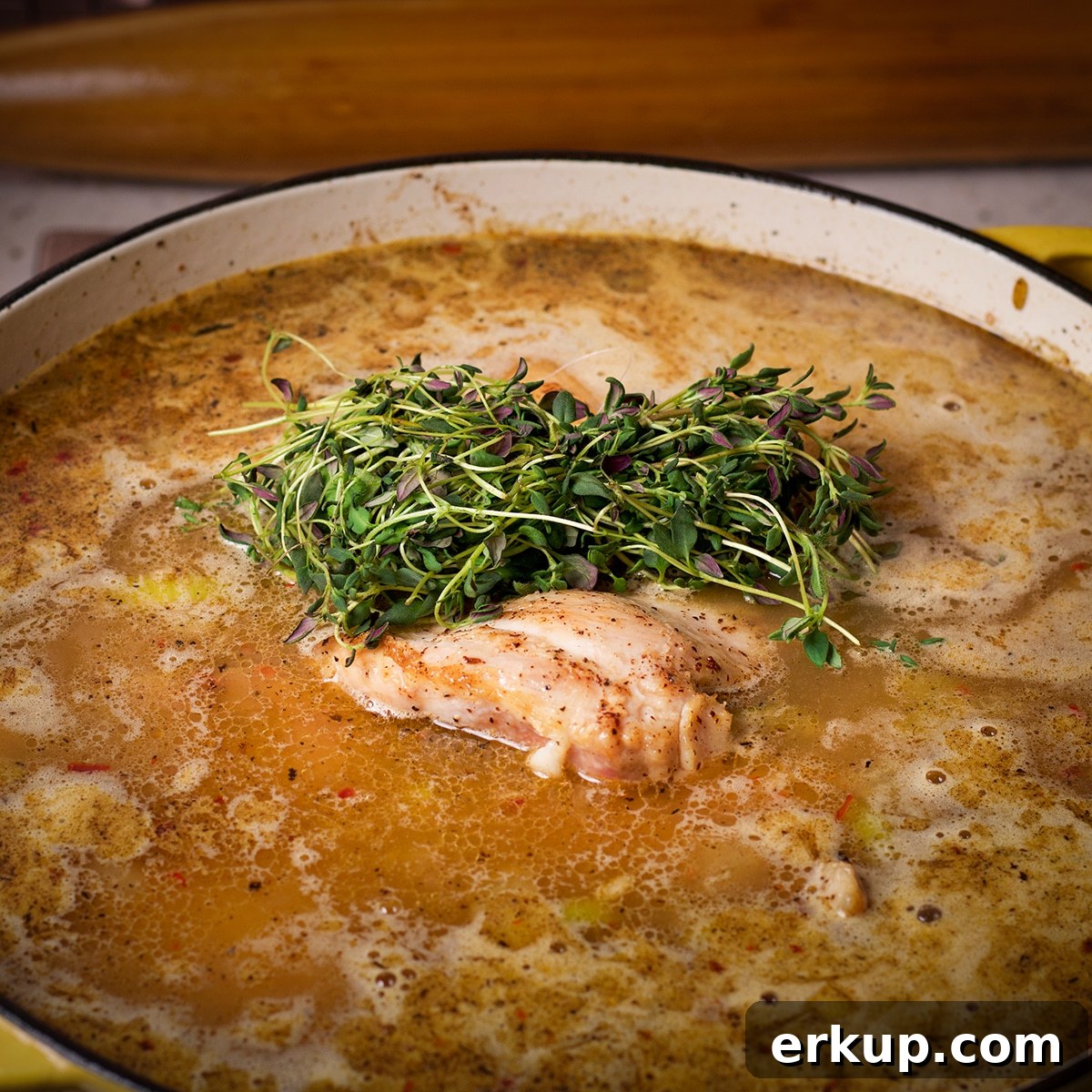 Add the browned chicken and bunch of fresh thyme to the broth to cook.