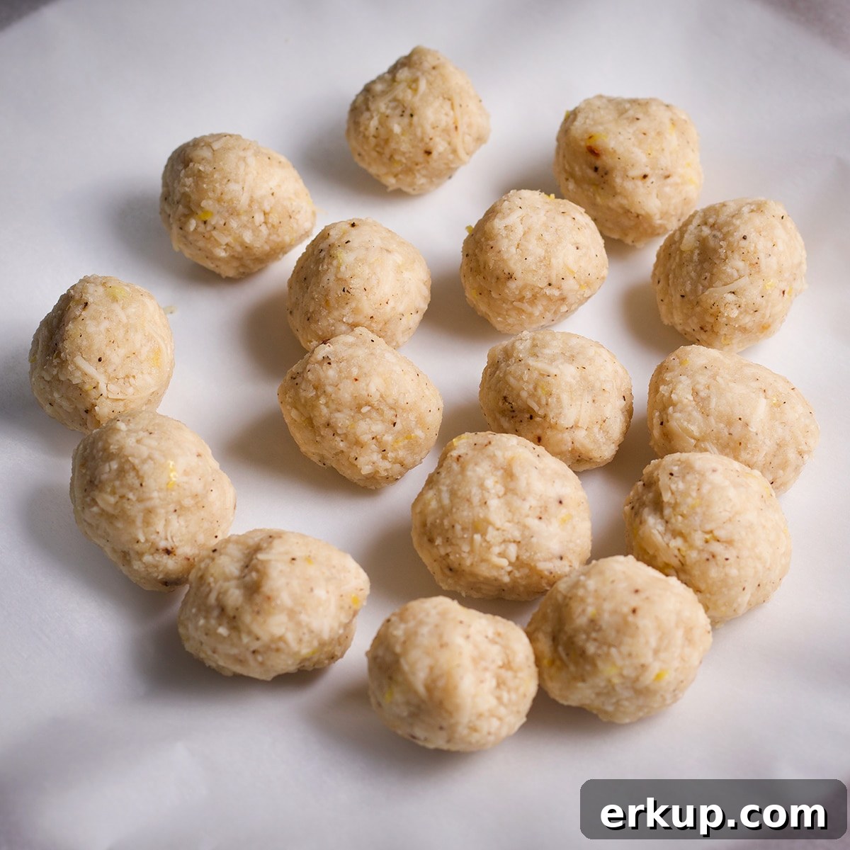 Parmesan dumplings on a parchment covered plate.