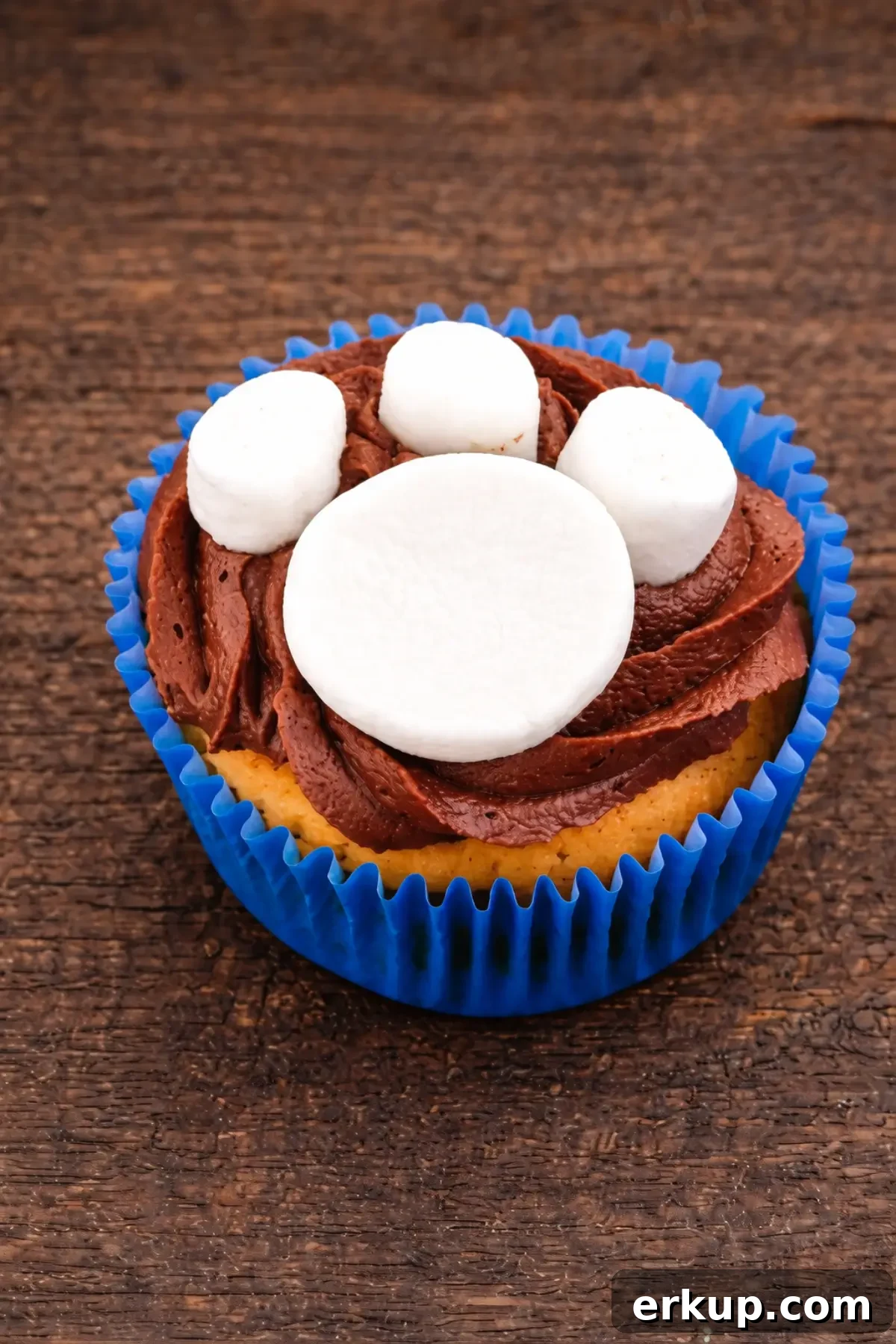 Close-up of a cupcake topped with chocolate icing and marshmallows shaped like a paw print.