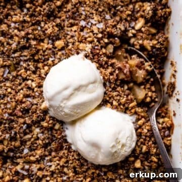 paleo apple crisp in a white casserole dish with vanilla ice cream scoops on top