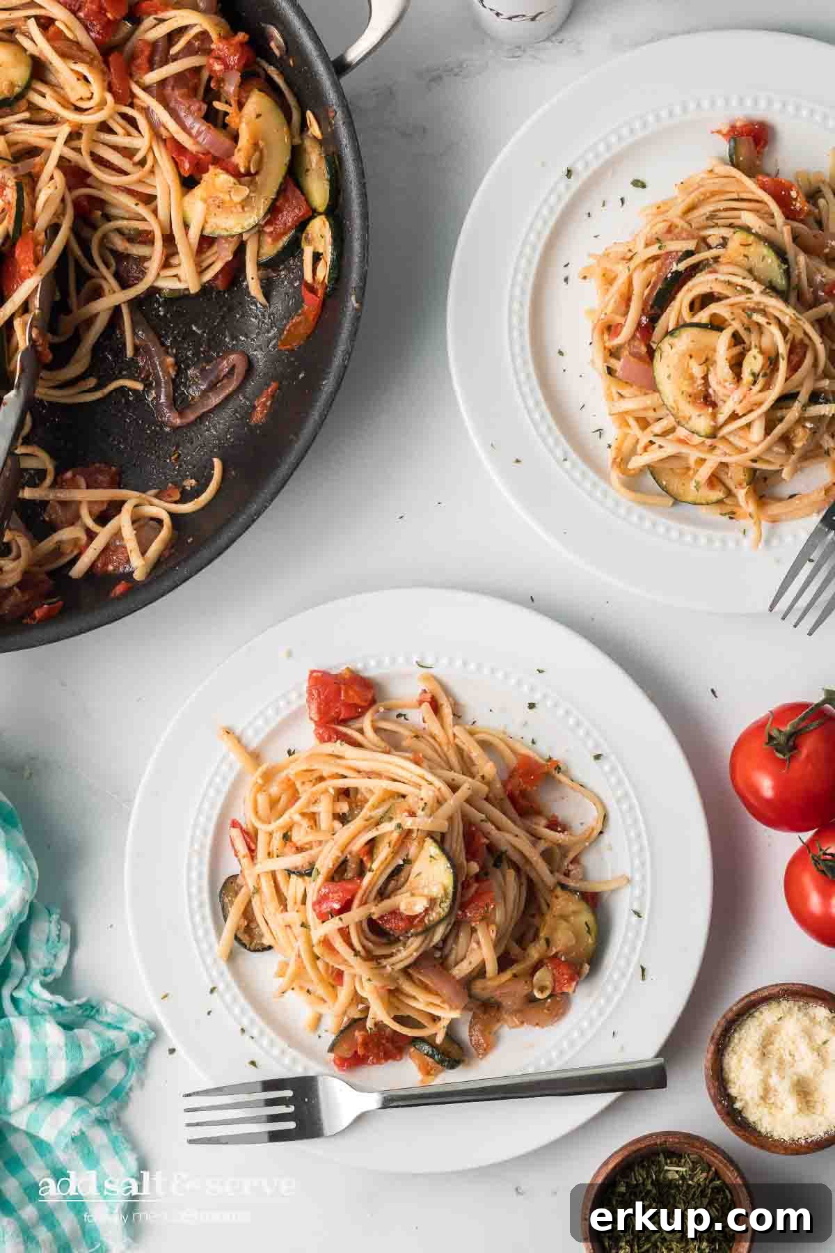 Lemon Garlic Zucchini Linguine with Parmesan 5 Linguine with tomatoes, garlic, zucchini, onion, and herbs on a plate with skillet of remaining zucchini linguine recipe.
