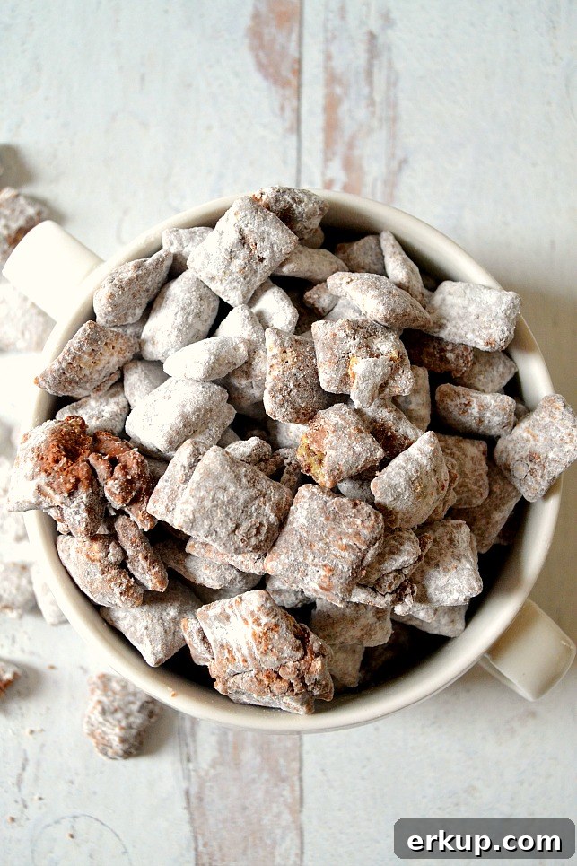 White bowl filled with muddy buddies on a white wood board