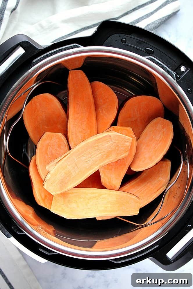 Overhead shot of sweet potatoes sliced in half, stacked on trivet in Instant Pot.