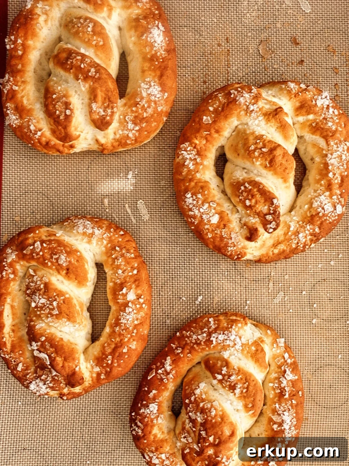 four pretzels on silicone baking mat.