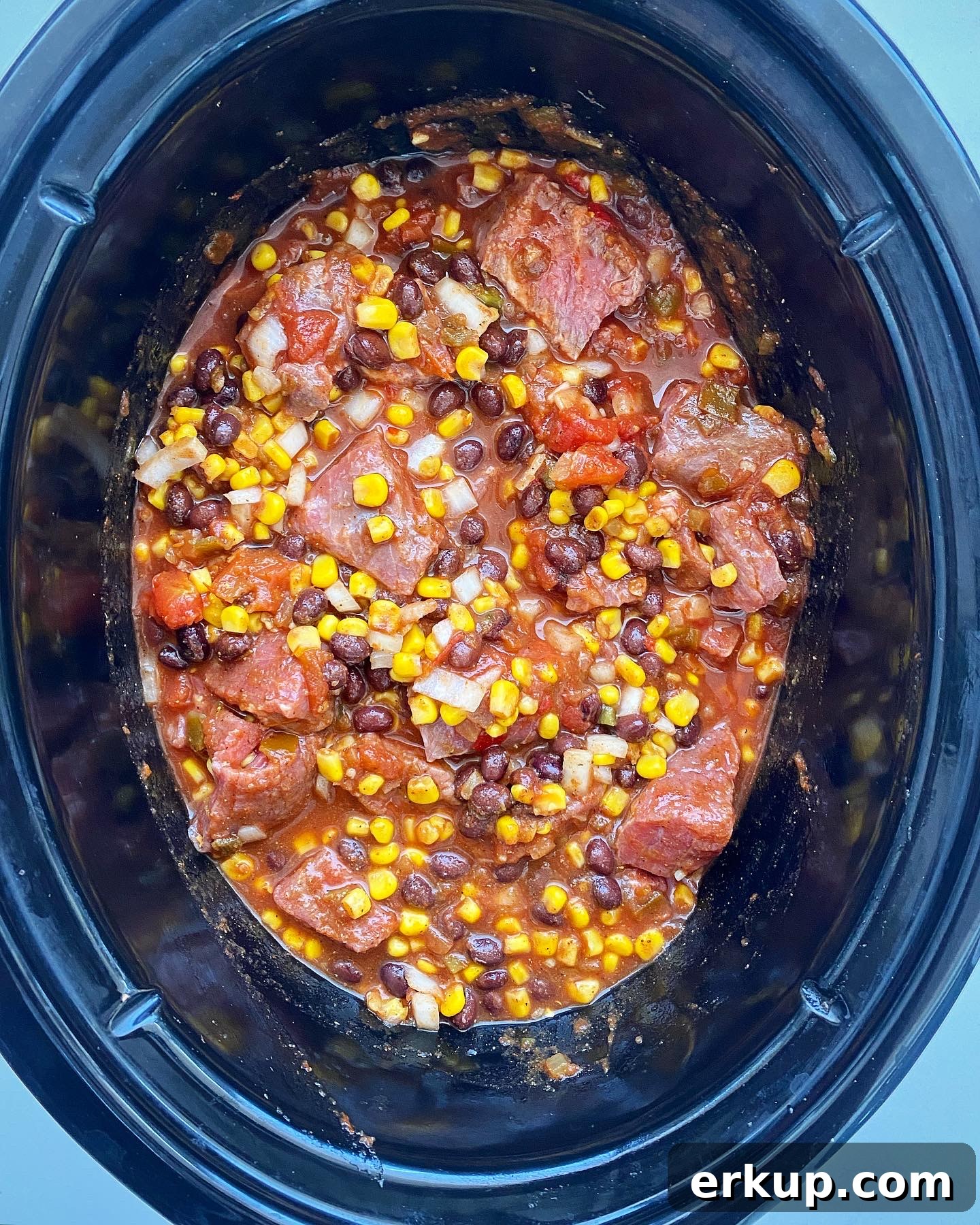 Slow Cooker Salsa Beef Stew Recipe 4 overhead shot of uncooked salsa beef stew in a black slow cooker