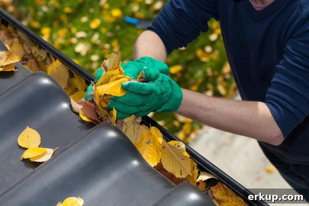 man with gloved hands removing autumn leaves from gutters
