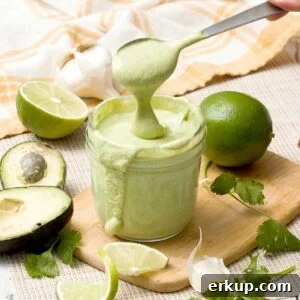 A spoon lifting avocado lime ranch dressing out of a mason jar.