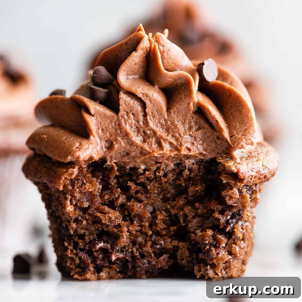 up close front view of a chocolate cupcake cut in half with chocolate frosting